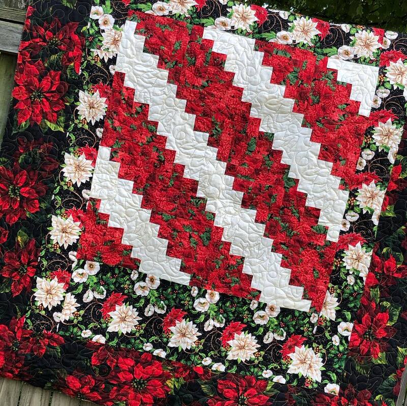 A Log Cabin Christmas quilt, highlighted with poinsettias, machine quilted by Amy Martin of Peaceful Quilts in Lafayette Indiana