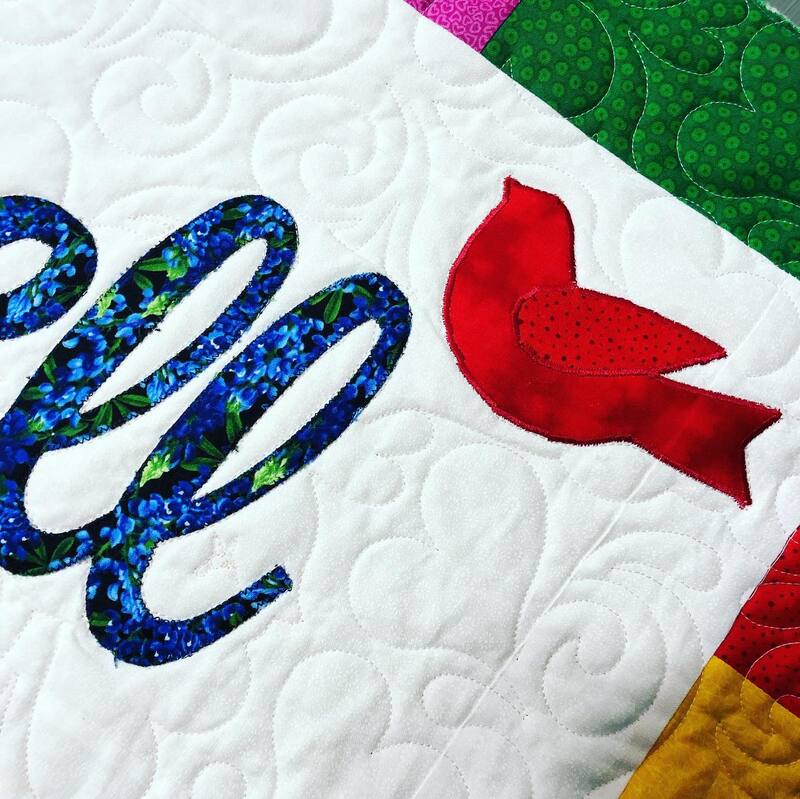 A red bird applique on a custom quilt by Amy Martin of Peaceful Quilts in Lafayette Indiana