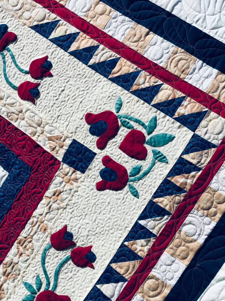 Background fill provides allows the applique to pop on this round robin quilt custom quilted by Amy Martin of Peaceful Quilts in Lafayette Indiana
