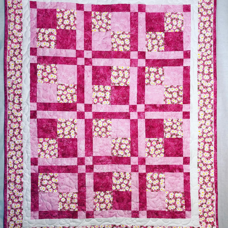 Disappearing 9 patch pink baby quilt, pieced and machine quilted by Amy Martin of Peaceful Quilts located in Lafayette Indiana. 